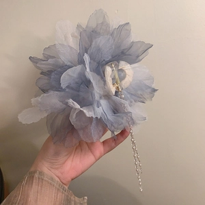 Close-up of large blue flower hair claw with elegant hanging pearl tassel detail