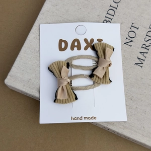 Detail view of corduroy and satin bow hair clips on display card over a vintage book