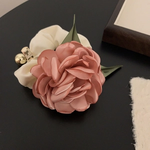 Close-up of a satin rose hair scrunchie in dusty pink with green leaves and gold bead
