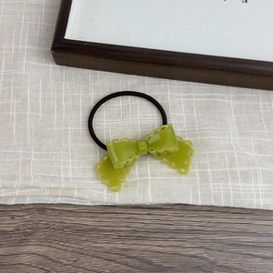 Detailed macro view of the pastel green resin bow hair tie with hollow lace edges