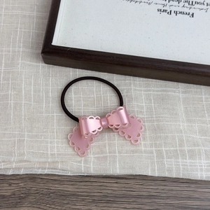 Detail of pink resin bow hair tie with hollow petal patterns and high elastic black band
