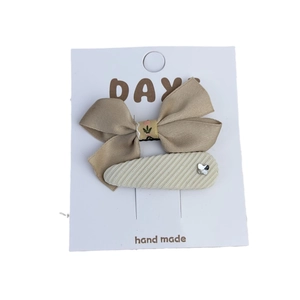 Two-piece set of khaki silk bow clip and beige fabric hairclip on a display card