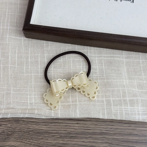 Detail of cream-colored hollow bow hair tie on linen fabric with elegant minimalist style