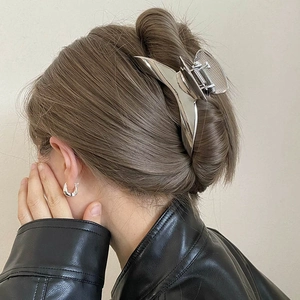 Minimalist silver metal hair claw clip and chunky U-shaped earrings on a stylish model