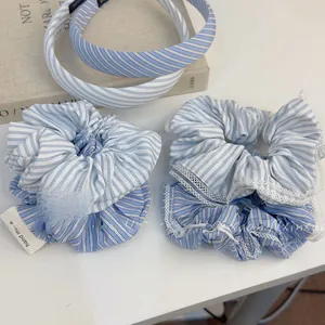 Detailed close-up of blue striped fabric hair scrunchies with white lace and handmade labels