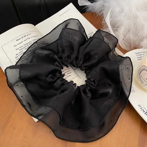 Close-up of large black polka dot mesh scrunchie with elegant ruffled texture details