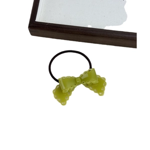 Elastic hair tie with a translucent green bow featuring intricate hollow wavy edges