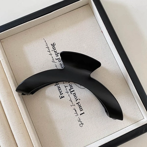 Close-up of minimalist black matte hair claw clip on cream velvet jewelry display tray