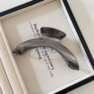 Macro shot of minimalist gunmetal grey arched hair claw with mirror finish texture