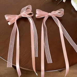 Détail de barrettes à nœuds en satin rose et dentelle avec rubans sur surface en bois