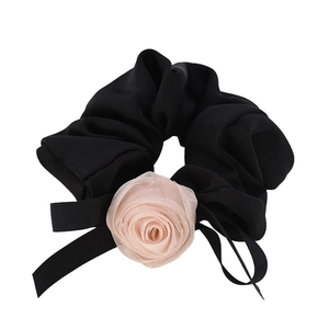 Chouchou noir élégant avec rose en maille rose et long ruban sur fond blanc épuré