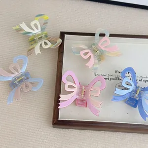 Collection of French cream bow hair claws in diverse pastel colors on a wooden tray