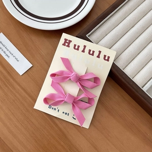 Dettaglio di due fermagli per capelli a fiocco rosa su carta esposta su legno liscio