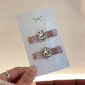 Close-up of pink satin bow hair clips with oversized gemstone and rhinestone accents