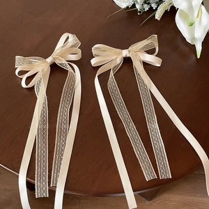 Détail de barrettes à nœuds élégants en dentelle et ruban crème sur bois sombre