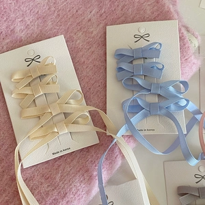 Set de pinces à cheveux avec nœuds roses et rubans jaune pâle et bleu sur fond en peluche