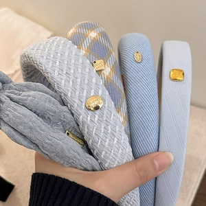 Serre-têtes en tissu bleu et gris avec logo doré pour une coiffure volumineuse et chic