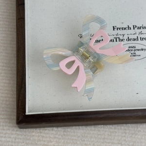 Detail of macaron stripe bow hair claw with acetate texture and strong gold spring