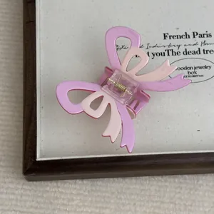 Detail view of pink bow hair claw clip with acetate texture and golden metal spring