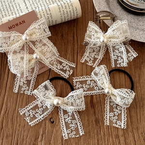 French vintage cream lace bow hair clip set with elegant pearls on a rustic wood background