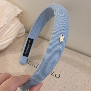 Détail du serre-tête bleu avec texture côtelée, emblème doré et étiquette fait main