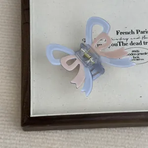 Close-up of blue and pink bow hair claw clip with matte acetate texture in display box