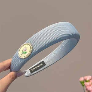 Détail du serre-tête tulipe bleu avec perles, texture tissu et étiquette faite main