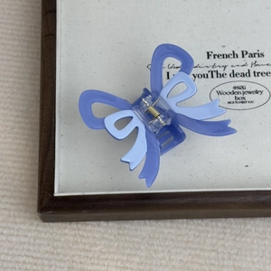 Detailed macro view of a lavender acetate bow hair claw clip in a wooden box display