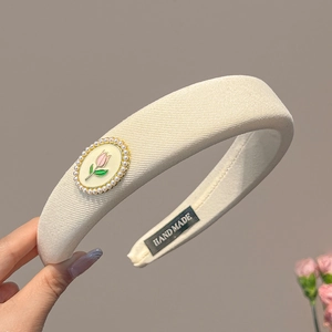 Détail du serre-tête en tissu crème fait main avec ornement tulipe et perles