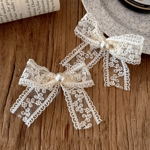 Detailed macro view of white lace bow hair clips with pearls on a vintage background