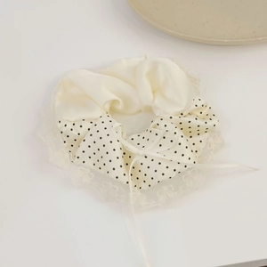 Detailed close-up of cream satin hair scrunchie with polka dots and lace edge ribbon