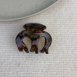 Dettaglio molletta per capelli in acetato ambrato con scritta dorata Barrette la France