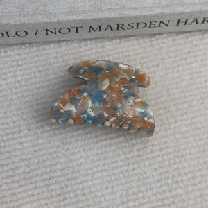Détail de la pince à cheveux en acétate marbré avec strass sur un tissu en maille