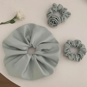 Three-piece set of mint green satin scrunchies featuring a 3D fabric rose floral detail