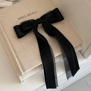 Détail montrant les couches de satin noir et de tissu organza sur l'élégante pince à cheveux