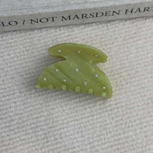 Gros plan d'une pince à cheveux en acétate vert clair avec texture marbrée et strass brillants