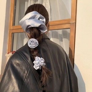 Three-piece set of elegant grey satin flower scrunchies worn by a model in soft natural light