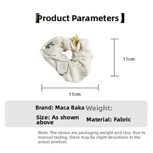 Detail showing the 11cm diameter and cream fabric texture of the daisy pattern scrunchie