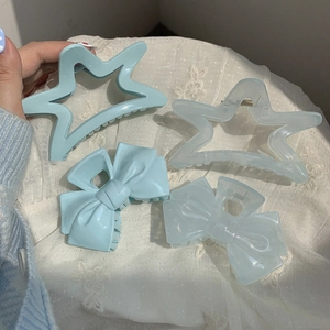 Set of four ice mint blue star and bow hair claws on white lace fabric background