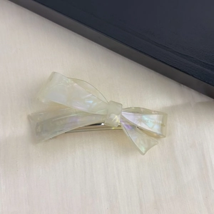 Detailed close-up of pearlescent acetate bow hair clip with silver spring metal fastener