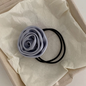 Detailed view of the elegant grey silk rose hair tie with elastic band on gift packaging