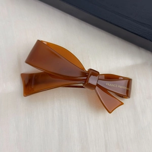 Detail of amber acetate bow hair clip with gold France Handmade lettering on fabric