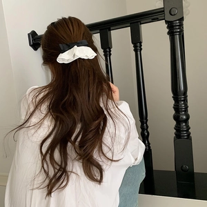 Barrette élégante en satin noir avec dentelle blanche portée sur cheveux longs bruns