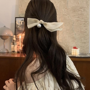 Eleganter cremeweißer Haargummi mit Schleife und Perle an Modell mit braunem Haar