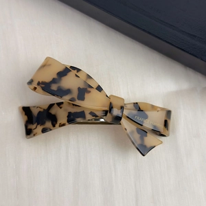 Detail view of handmade tortoiseshell acetate bow hair clip with silver spring clasp