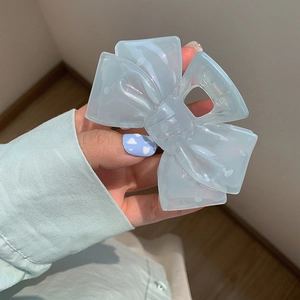 Detail of light blue bow hair claw clip with white cloud pattern and translucent finish