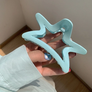 Macro shot of a mint blue star shaped hair claw clip with a matte resin finish