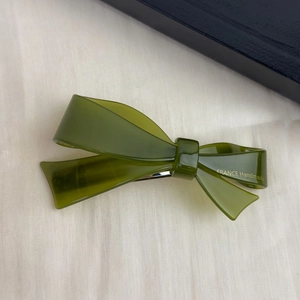 Close-up of olive green acetate bow hair clip with gold France Handmade lettering