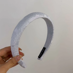 Détail de la texture dentelle du serre-tête gris avec étiquette Hand Made