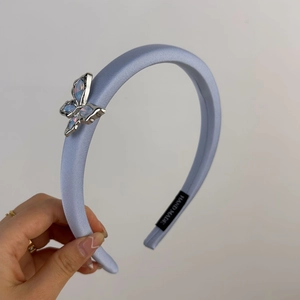 Détail d'un serre-tête en satin bleu clair avec papillon en cristal et label